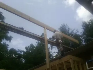 Carpenter setting a ridge beam over a new addition frame — Ice Dam Removal by Roofing Brothers in Oakland Gardens