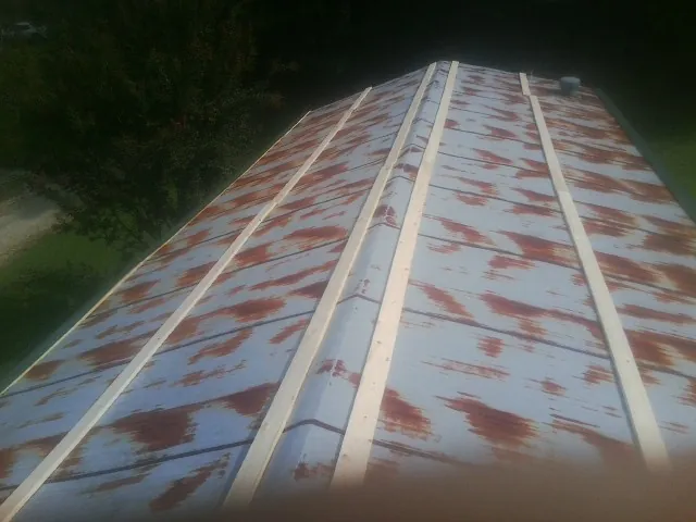 Rusted metal roof panels with new wood purlins before replacement — Storm Damage Roof Repair in Oakland Gardens by Roofing Brothers
