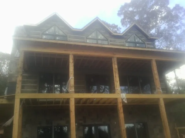 Dormers and porch framing on a large log home under construction — Roof Coating work by our crew in Oakland Gardens