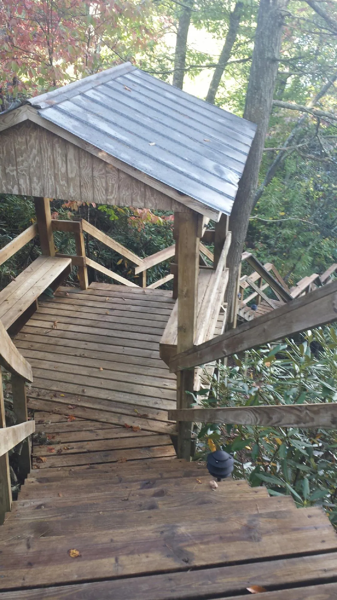Metal roofed shelter over wooden steps on a wooded walkway — Skylight Repair & Installation work by our crew in Oakland Gardens